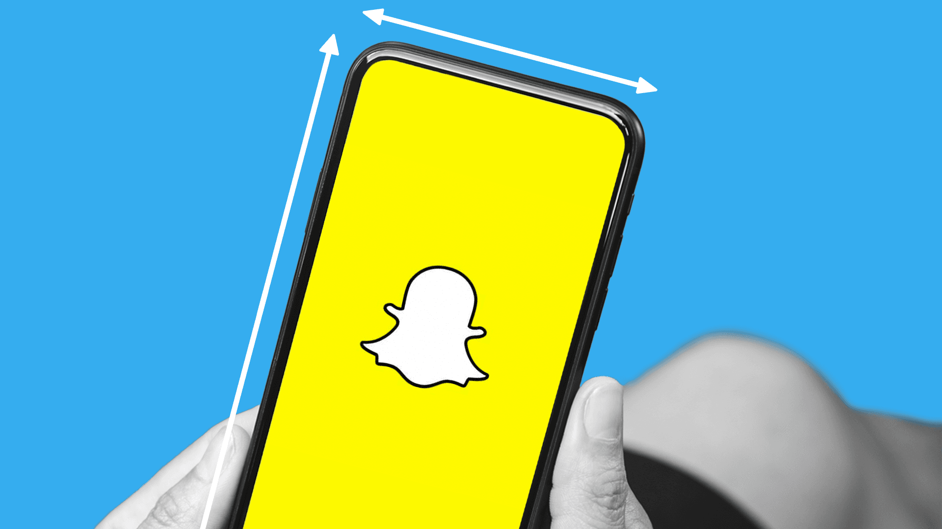 This photo features someone holding a smart phone. The phone is opened to Snapchat. The phone has lines on the sides to show the Snapchat video ad specs and sizes.